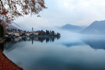 Serene lake panorama shrouded in light fog with reflections of surrounding mountains and autumn colors, panorama of the lake with light fog and sounds of nature