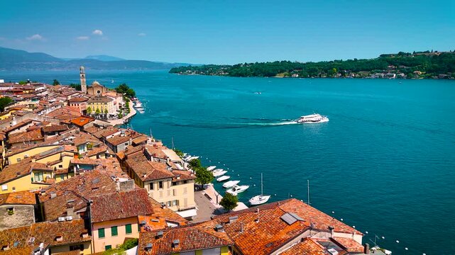 Aerial view of Salo, Italy with terracotta rooftops, lakeside promenade, and boats docked on the shore of Lake Garda on a sunny summer day
