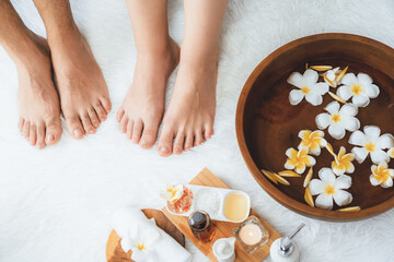 Couple indulges in blissful foot massage at luxurious spa salon for reflexology therapy in gentle day light ambiance resort or hotel foot spa. Quiescent