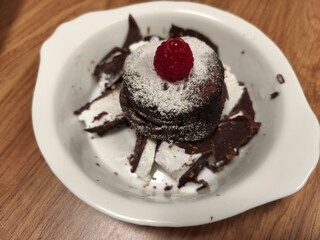 Chocolate cake sprinkled with powdered sugar and topped with raspberries