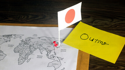 Travel to Japan concept, National Flag waving on world map with handwritten yellow sticky note, on a wooden table