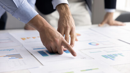 Data analysis, collaboration and strategic planning. Close up on hands pointing at charts and...
