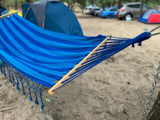 Empty blue hammock hanging between trees at campground