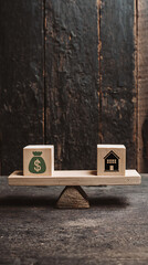 Wooden cubes with money and house symbols balanced on a scale image