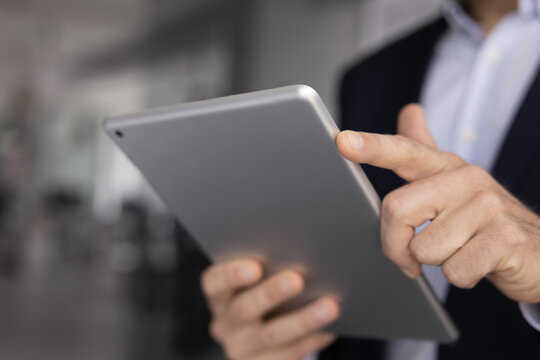 Close up of unknown professional man using digital tablet, chatting with colleague or client, typing message or email, web surfing information on internet, engaged in digital communication by business