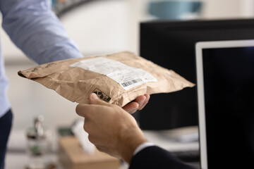 Close up of courier gives small parcel envelope to businessman client sits in workplace and...