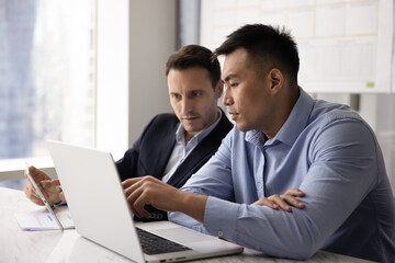 Obraz premium Team engaged in joint task completion or issues solution using digital tablet and modern laptop during teamwork in office. Two colleagues brainstorm ideas, review new corporate platform or software