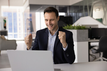 Middle-aged man sits at desk with laptop, receiving news of promotion, celebrate success, closing...
