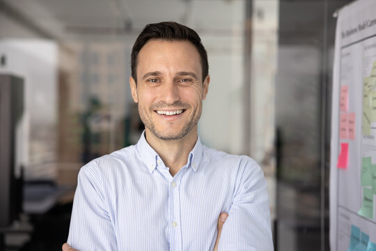 Head shot close up of middle-aged 40s businessman, CEO or executive dressed in casual shirt posing indoor, looks at camera, feel satisfied with career growth, exuding professionalism, office portrait - Powered by Adobe