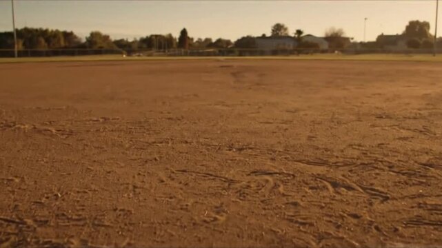 Lonely Baseball Bat Casting Long Shadow on Quiet Field with Etched Baselines