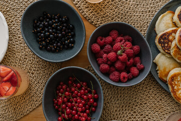 fresh raspberries, red current and black current in a bowl, aesthetic table setting with berries and pancakes	