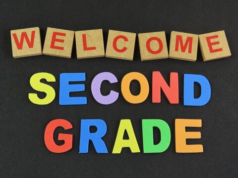 Wood letters form the word "Welcome" and multicolored eva foam letters form the expression "Second grade", referring to the elementary school days on black background. Back to school concept.