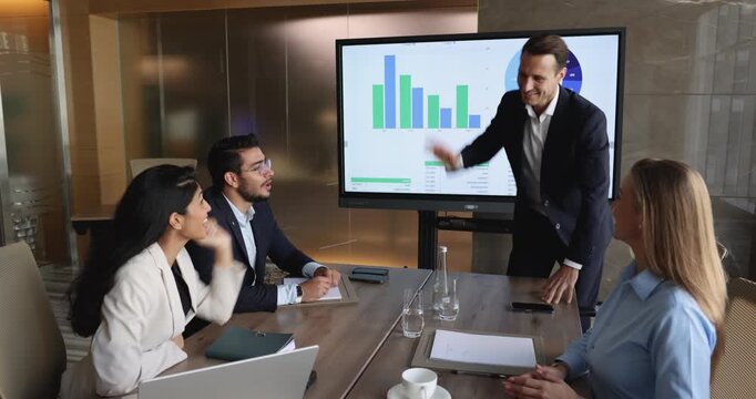 Team of four happy excited young business colleagues discussing successful product marketing strategy in meeting presentation room, group giving high five hands, celebrating goal achieving