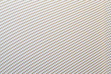 Metal mesh texture with perforated diagonal pattern of round holes closeup