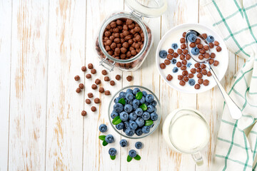 Quick breakfast for kids with chocolate corn balls and blueberry on a light kitchen table, top view.