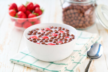 Healthy breakfast for kids with chocolate corn balls and strawberry on a light kitchen table, selective focus. Morning breakfast.