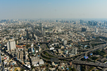 An aerial shot captures a sprawling urban landscape featuring towering buildings, complex highways,...