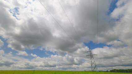 A detailed view of a high-voltage power tower standing tall with several cables hanging, an...
