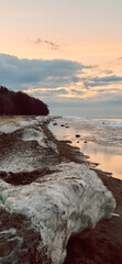 Peaceful scene of ice floes drifting in calm ocean waters with stunning sunset sky. Reflective...