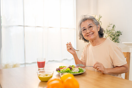 Portrait of Happy Asian senior woman having lunch or dinner at home. Elderly woman enjoy healthy lifestyle eating organic clean food vegetable and fruit. Retired people healthcare wellness self-care.