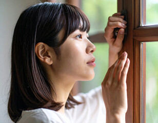 Fototapeta premium 窓から外を眺める若い女性/ Young woman looking out the window