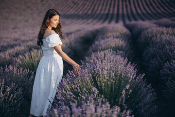 Young woman wearing white dress walking in lavender field