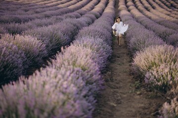Young girl running in a lavender field holding a wicker basket