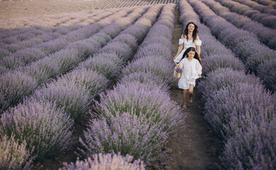 Mother and daughter walking through lavender field holding wicker basket