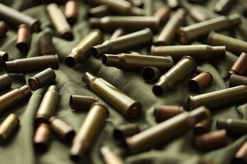 Many used rifle cartridges on military camo green fabric background