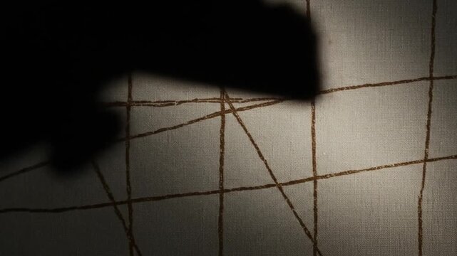 A close up of a textured wall with brown lines forming a grid and a dark shadow on the right