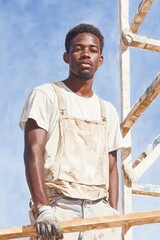 Young Black male plasterer demonstrating skill on scaffold in urban construction site during daylight hours