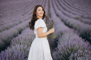 Woman wearing white dress holding lavender bouquet in lavender field