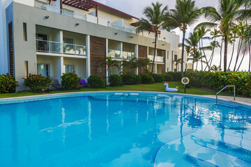 Modern hotel building with swimming pool and inflatable unicorn surrounded by tropical palm trees. Dominican Republic. Punta Cana.