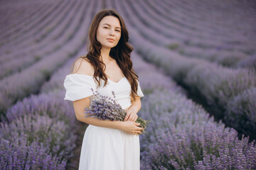 Woman wearing white dress holding lavender bouquet in lavender field