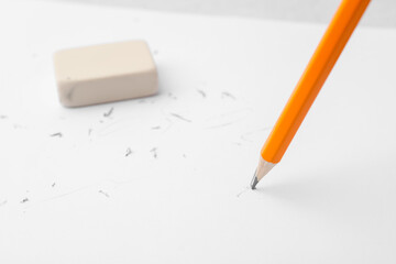 Graphite pencil and eraser on paper sheet, closeup