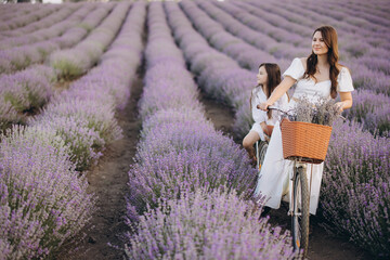 Mother and daughter riding vintage bicycle in lavender field