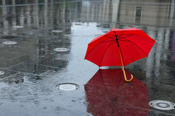 Red umbrella under heavy rain outdoors, space for text