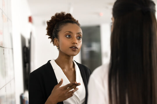 Close up of African professional business woman speaking with female colleague in office, having serious discussion or problem-solving conversation, share important information regarding joint task