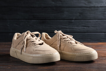 Pair of beige sneakers on wooden surface, closeup