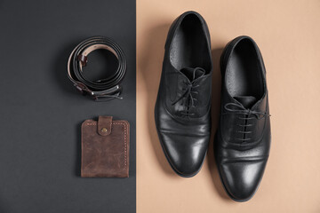 Pair of black leather shoes, purse and belt on color background, flat lay