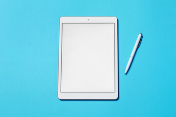 Tablet and pen on light blue background, flat lay