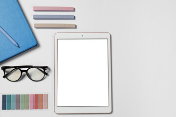 Tablet, different stationery and glasses on white background, flat lay. Space for text