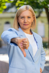 Sad upset disappointed Caucasian mature businesswoman female woman in formal suit showing thumb...