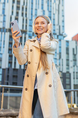 Joyful overjoyed mature businesswoman in coat listens to favorite energetic disco and rock n roll...