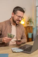 Planning budget. Rich happy businessman counting money dollar cash using laptop calculate domestic...