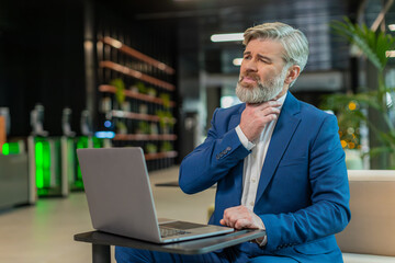 Sick businessman talking on video call having sore throat, coughs and works with laptop. Stressed...