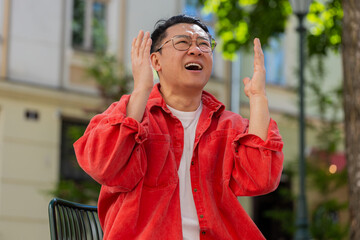 Sad unhappy Asian middle-aged man suffers from unfair situation outdoors. Problem, feeling bad,...