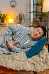 Mature ill sick man lying on couch feeling sudden strong abdominal stomach ache, gastritis problem....