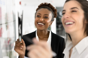 Two happy women marking successful milestone or completed tasks on calendar, discuss future plans,...
