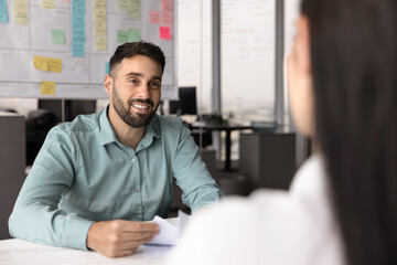 Recruiter holding resume and listening female, vacancy candidature seated at table in modern...